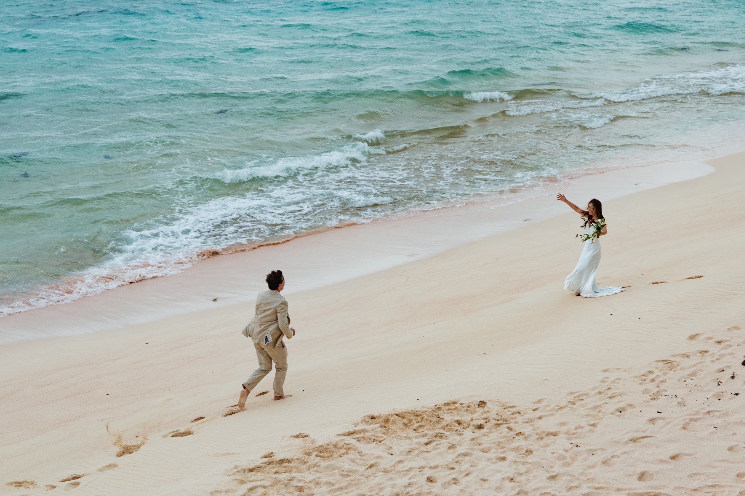 Child running along the pink sand toward the bride on a Bermuda beach