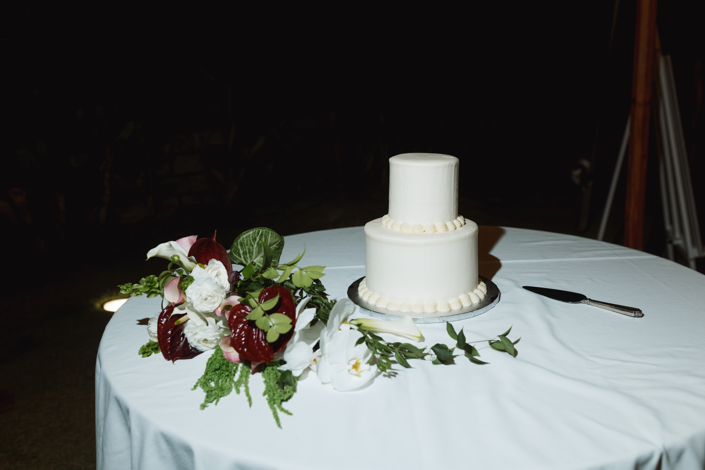 Wedding cake dressed with dark florals at night