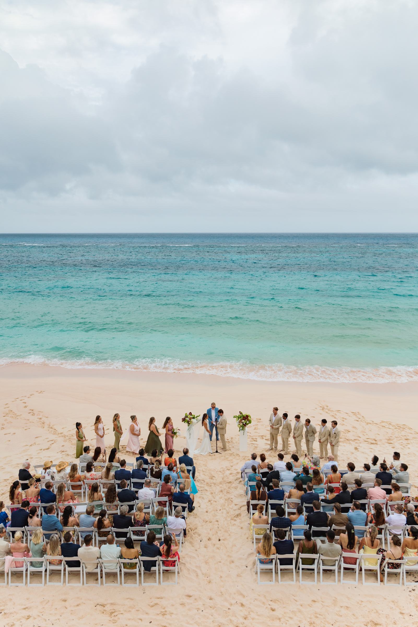 Beach ceremony seen from above with the guests seated on the sand