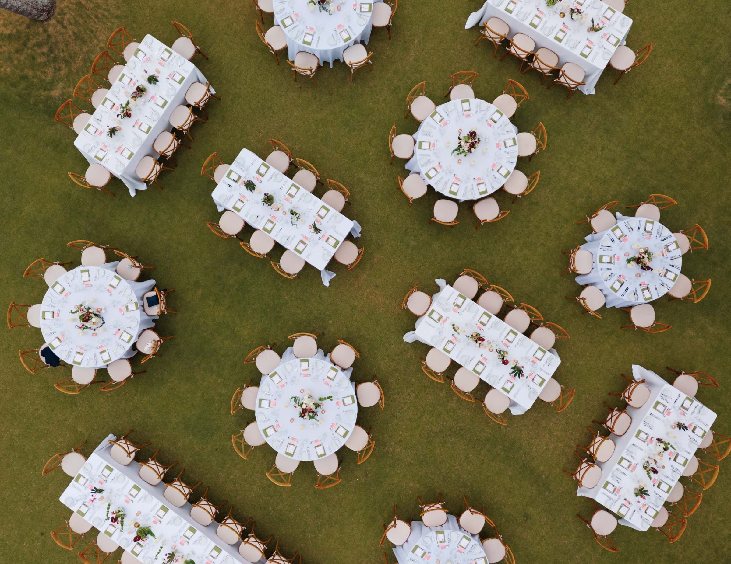 Aerial view of the reception tables set on the lawn above the beach