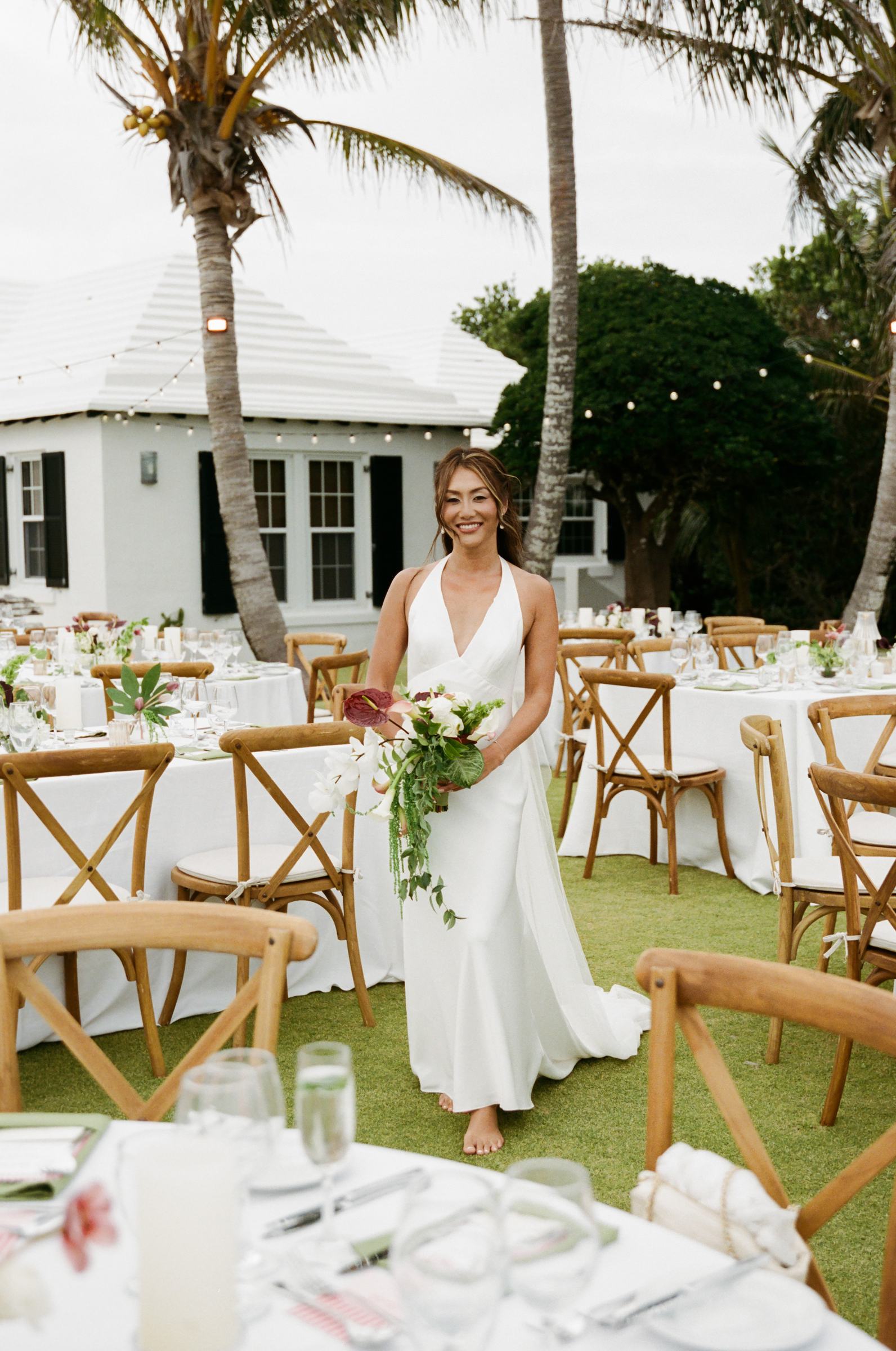 Bride walking alone through the set reception with her bouquet, shot on film
