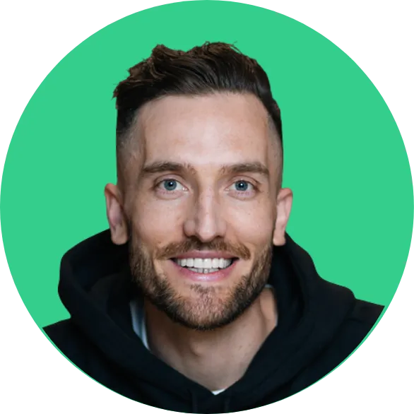 Smiling man with short dark hair, beard, and blue eyes wearing a black hoodie against a green background.