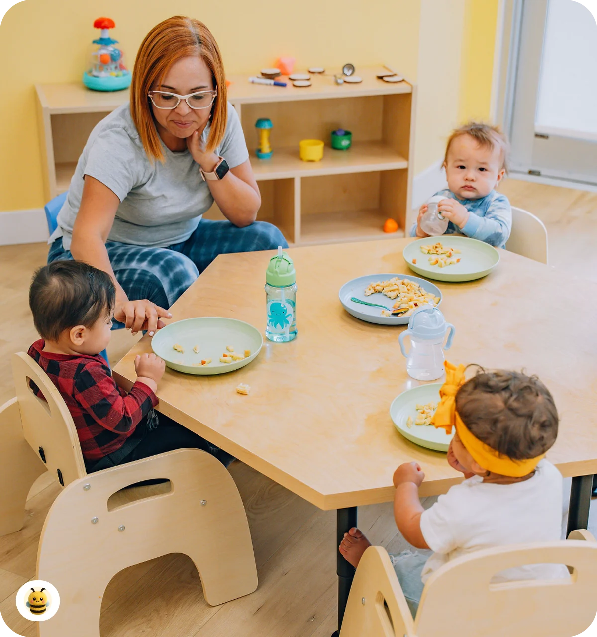 A woman is sitting at the table with kids while they are eating