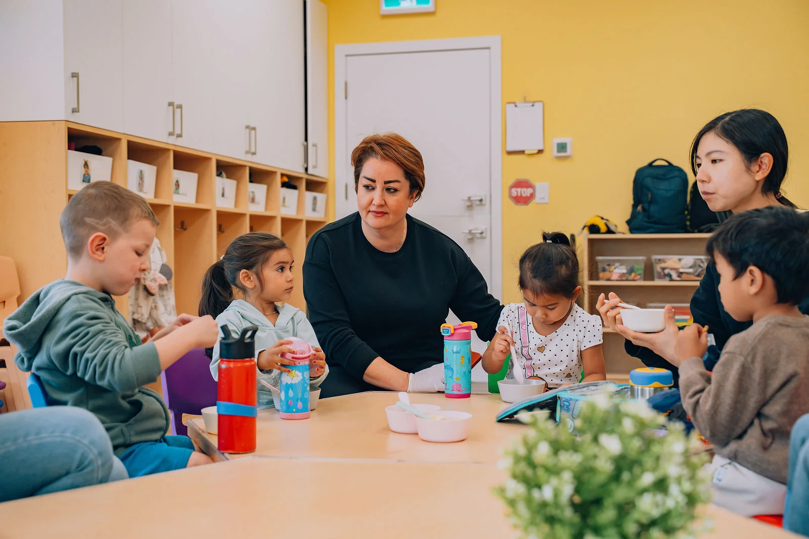 A woman is sitting at the table with kids