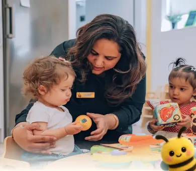 B Kids educator playing with toddlers in a bright classroom