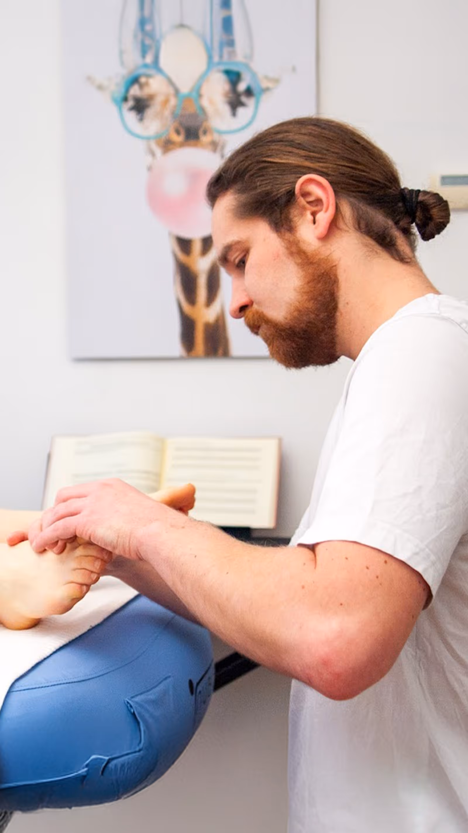 Der Heilmasseur Markus Anderle massiert Füße einer entspannten Kundin in Linz