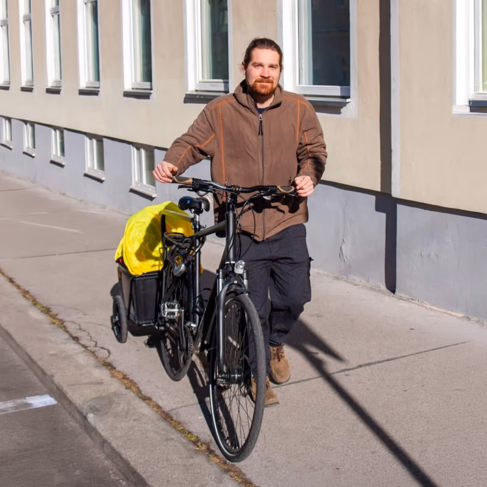 Markus Anderle mit einem schwarzen Lastenrad mit mobiler Massageliege auf einem Gehsteig