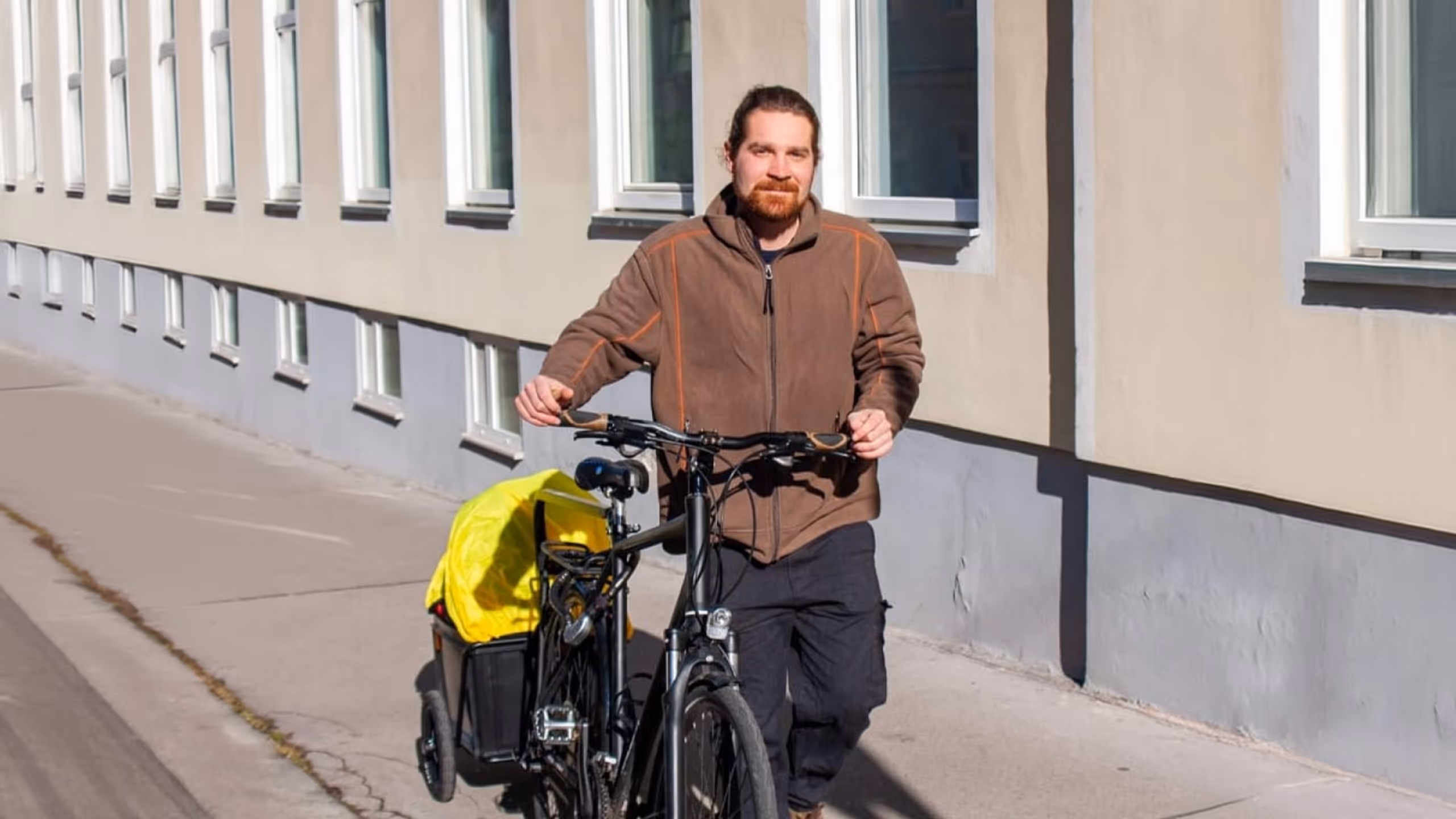 Markus Anderle mit einem schwarzen Lastenrad mit mobiler Massageliege auf einem Gehsteig