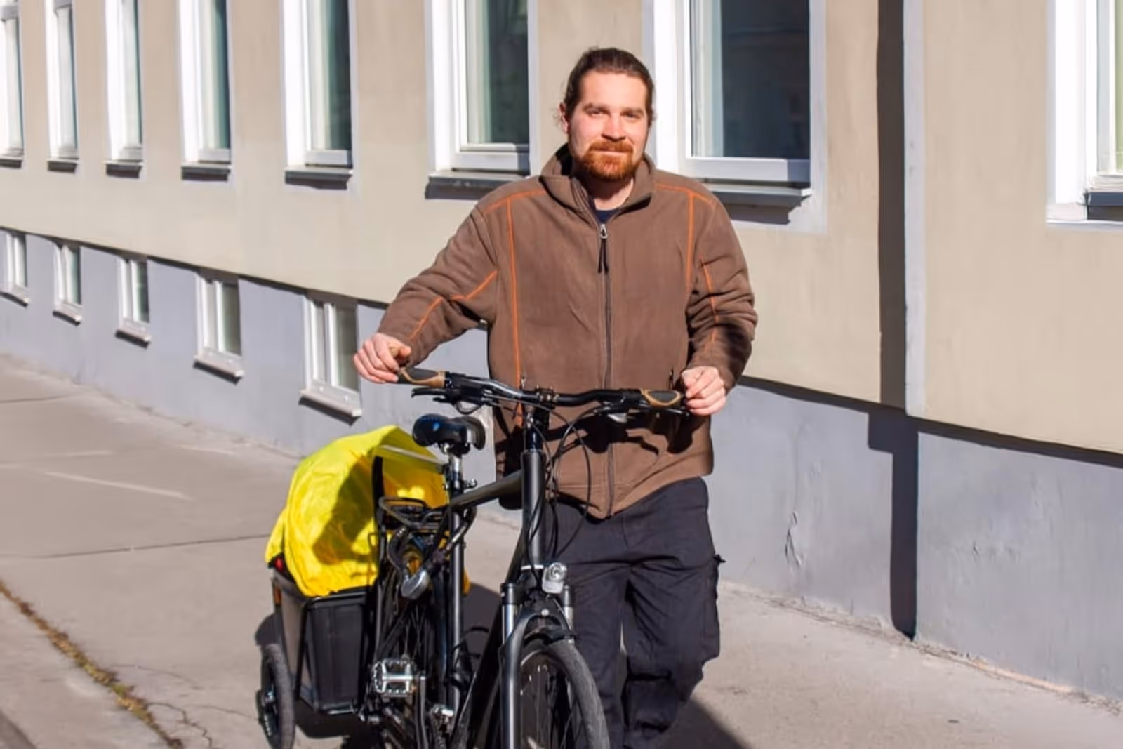 Markus Anderle mit einem schwarzen Lastenrad mit mobiler Massageliege auf einem Gehsteig