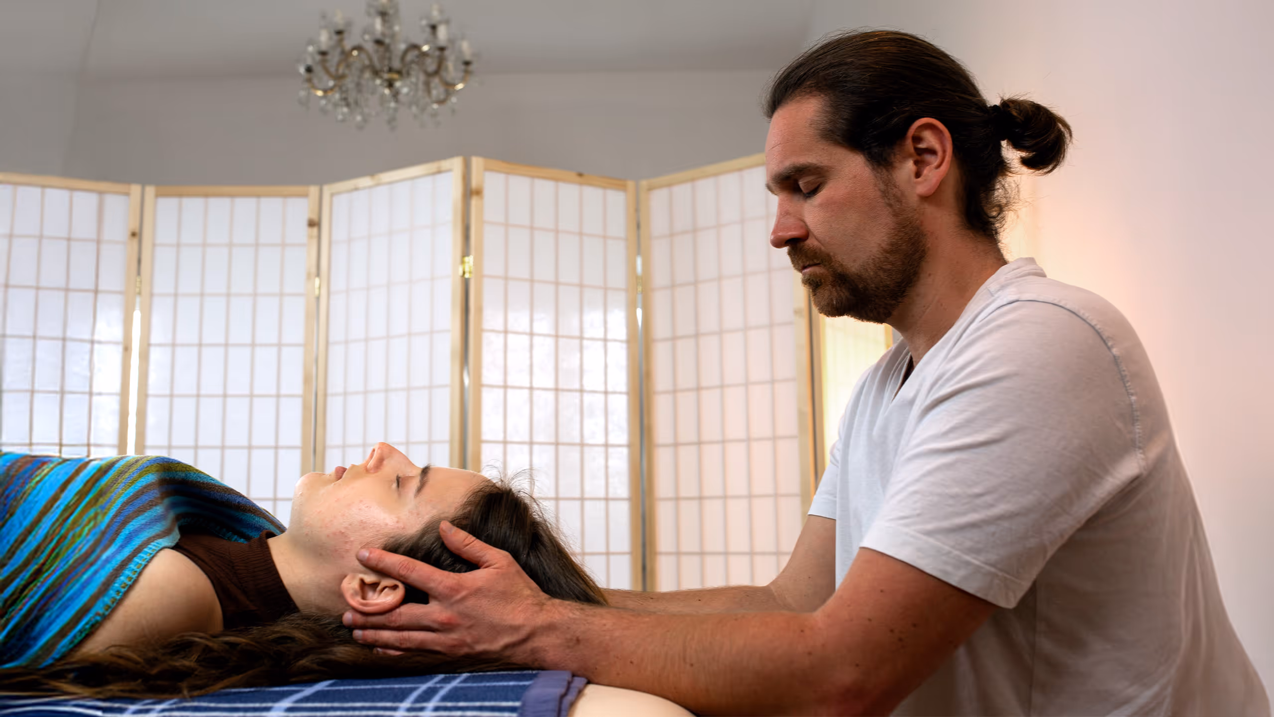 Person führt eine Cranio Sacrale Behandlung an einer liegenden Person mit geschlossenen Augen durch