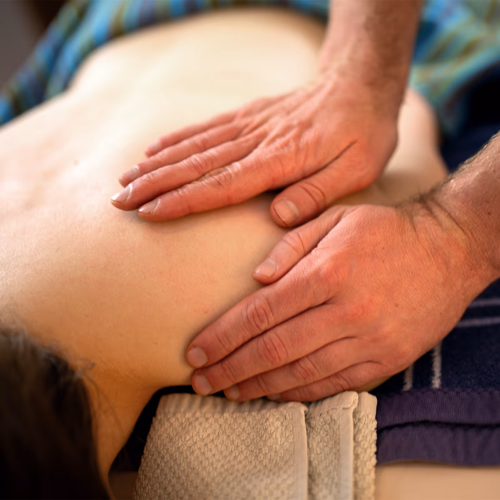 Heilmasseur legt Hände auf die Schultern eines Patienten