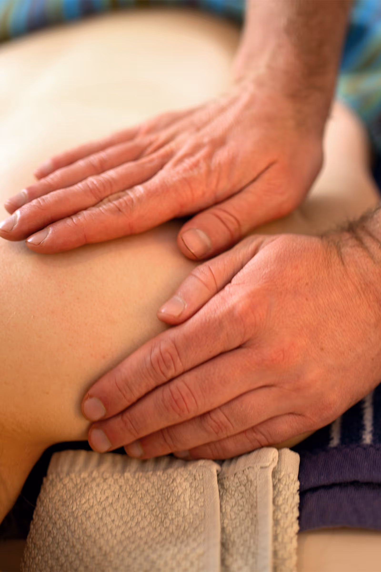 Heilmasseur legt Hände auf die Schultern eines Patienten
