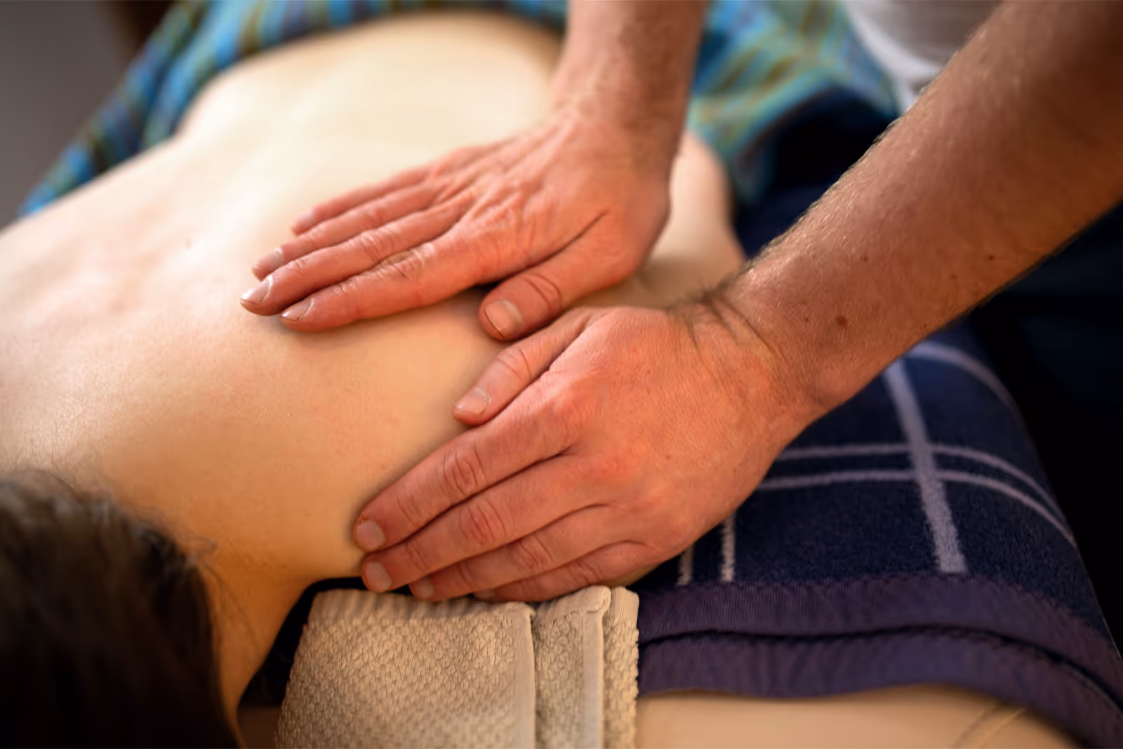 Heilmasseur legt Hände auf die Schultern eines Patienten
