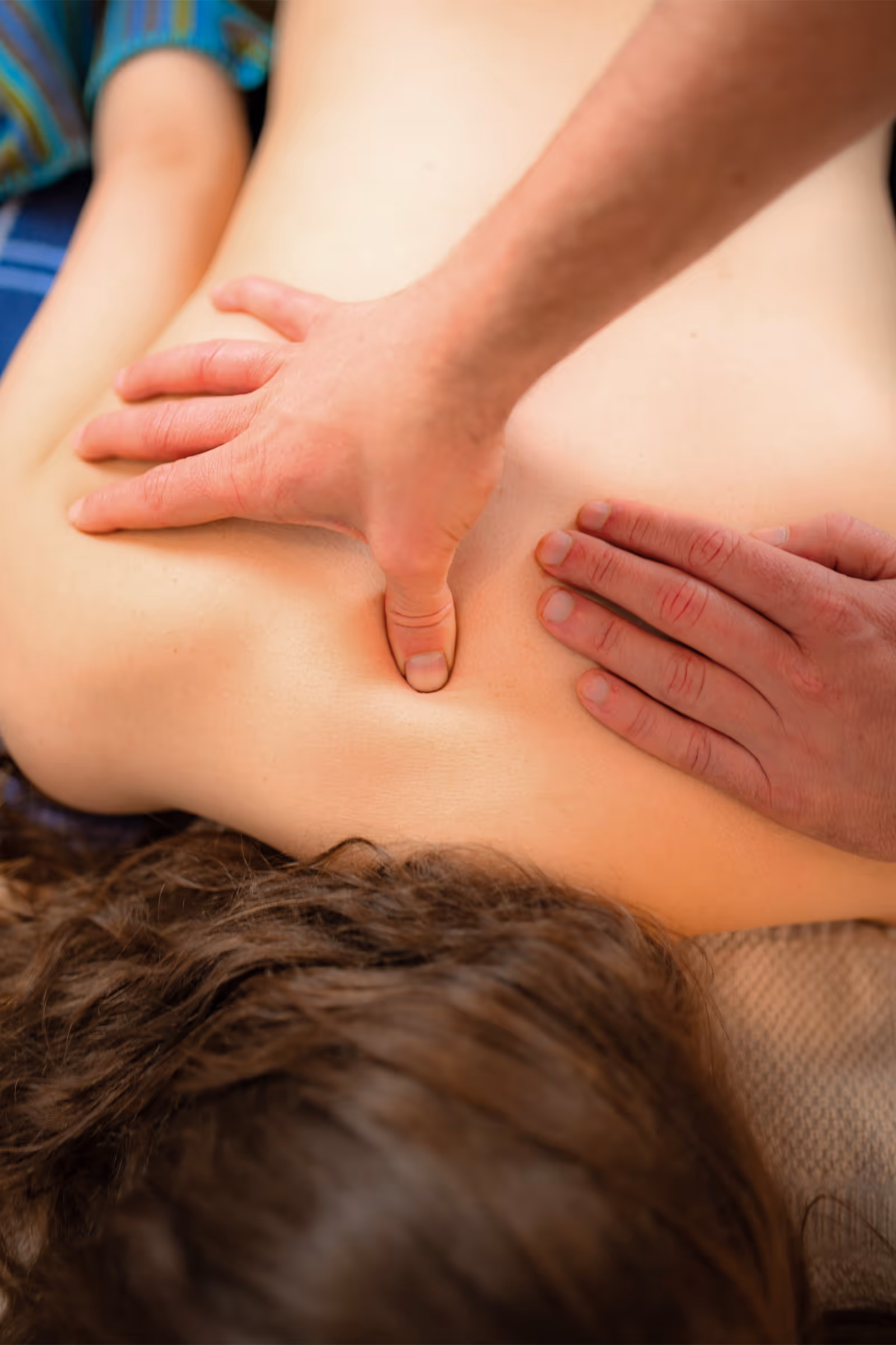 Heilmasseur übt sanft Druck zwischen den Schulterblättern einer Patientin aus