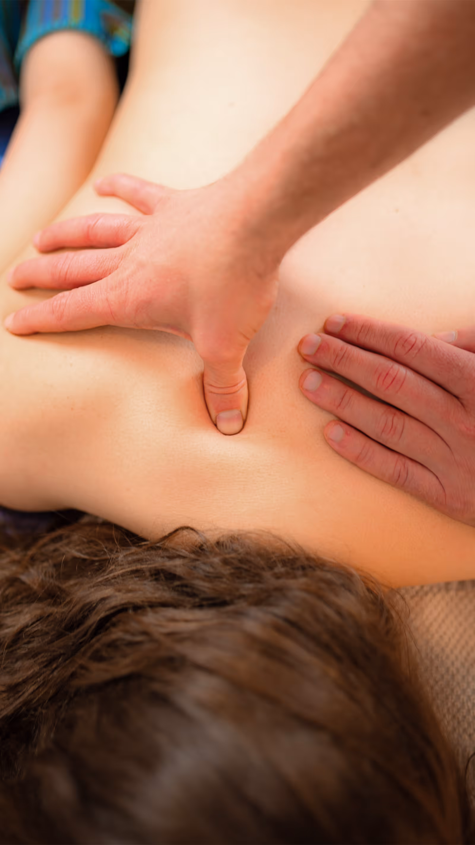 Heilmasseur übt sanft Druck zwischen den Schulterblättern einer Patientin aus