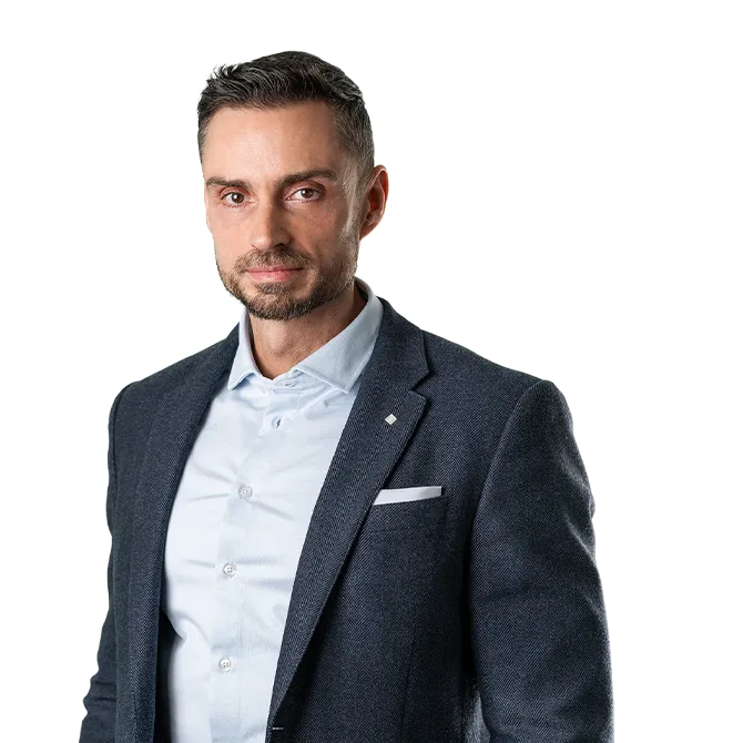 Confident man with short dark hair and beard wearing a blue blazer and light blue shirt against a white background.
