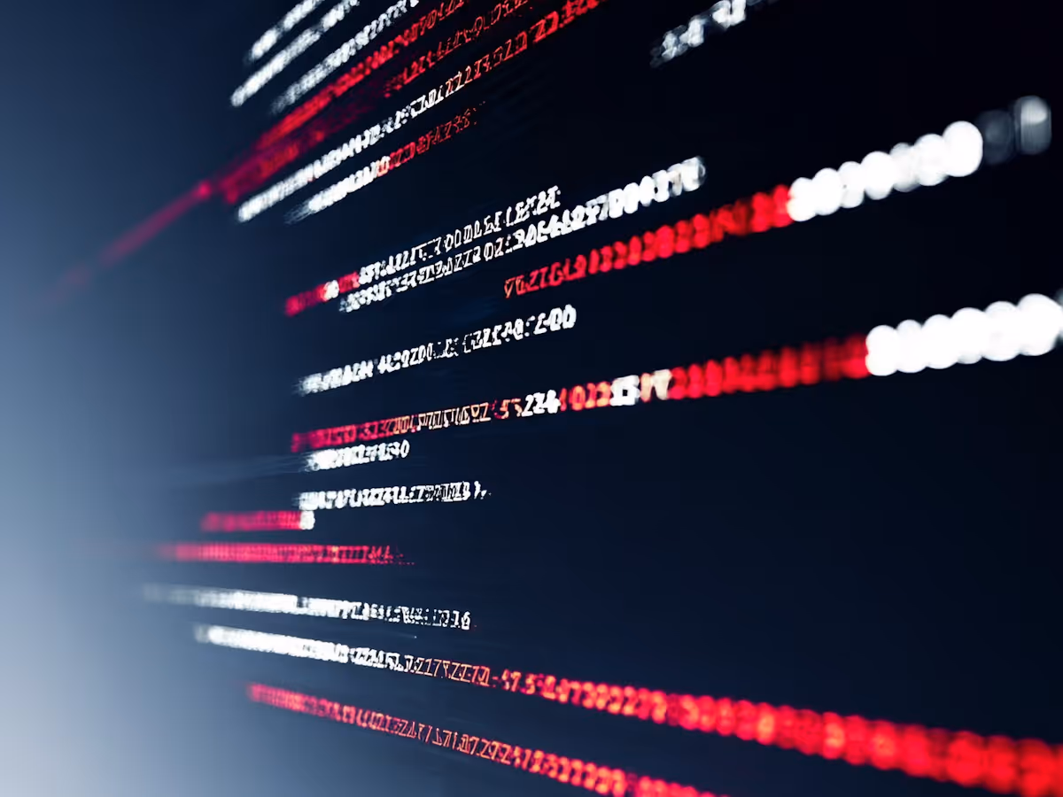 Diffust fokus på rader av röd och vit kod mot en mörk bakgrund, med futuristisk teknisk känsla.