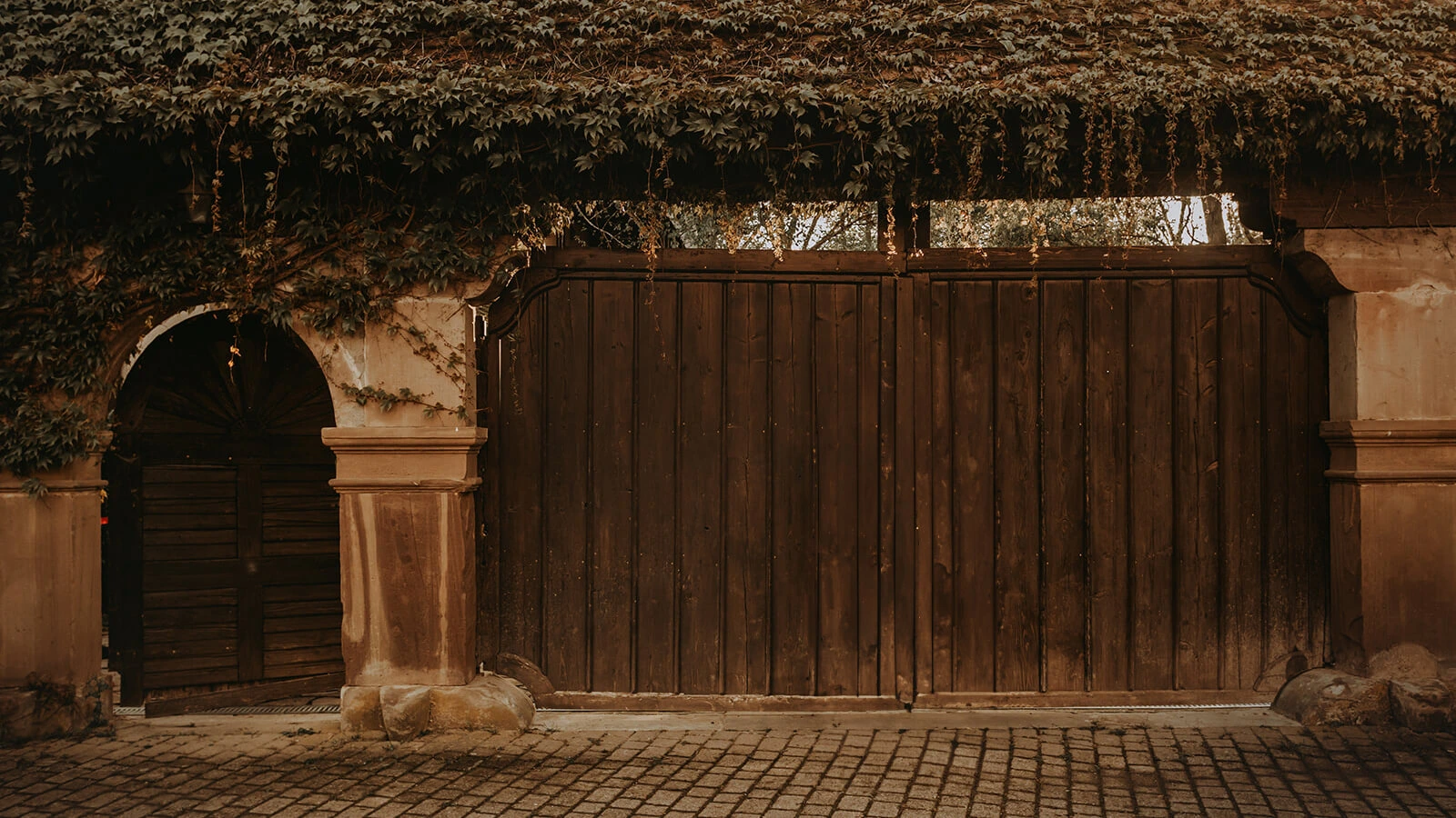 Le porche de la ferme Marie Hélène, devanture avec une grande porte en bois et une plus petite porte ronde