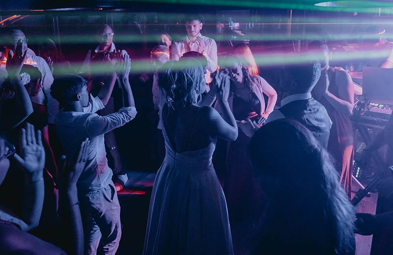 Soirée de mariage animée à La Ferme Marie Hélène, avec la mariée et les invités dansant sous des lumières colorées.