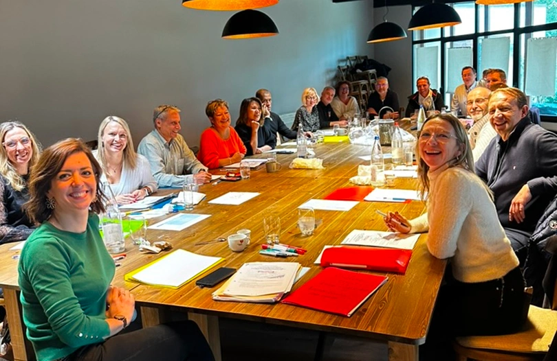 Participants réunis autour d’une grande table en bois pour un séminaire à La Ferme Marie Hélène, dans une ambiance chaleureuse.
