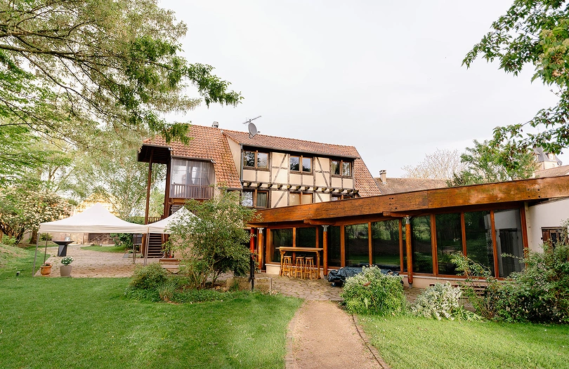 Bâtisse en bois et pierre de La Ferme Marie Hélène, nichée dans un écrin de verdure propice aux événements et séminaires.