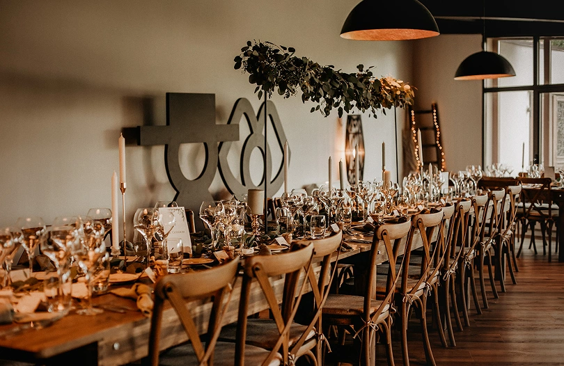 Grande tablée élégamment dressée pour un repas de mariage à La Ferme Marie Hélène, avec bougies et décoration naturelle.