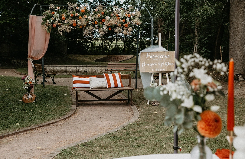 Arche florale et banc décoré pour une cérémonie de mariage romantique dans le jardin de La Ferme Marie Hélène.