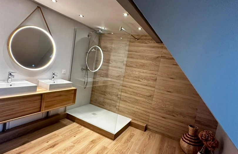 Salle de bain moderne de la ferme Marie Hélène avec douche à l’italienne, double vasque et miroir rond suspendu.