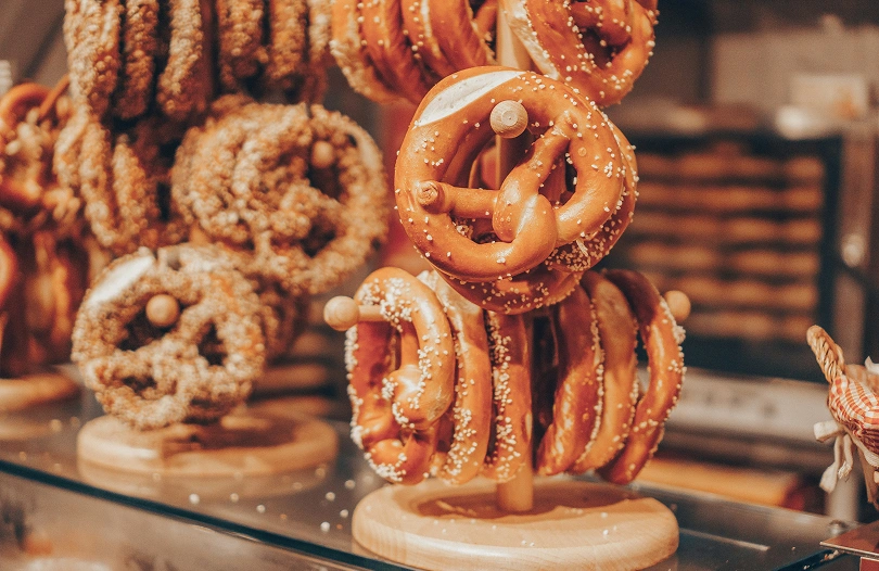 Présentoir en bois rempli de bretzels dorés et saupoudrés de sel dans une boulangerie artisanale.