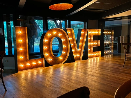 Grandes lettres lumineuses formant le mot "LOVE", parfaites pour une ambiance romantique lors d’un mariage à La Ferme Marie Hélène.