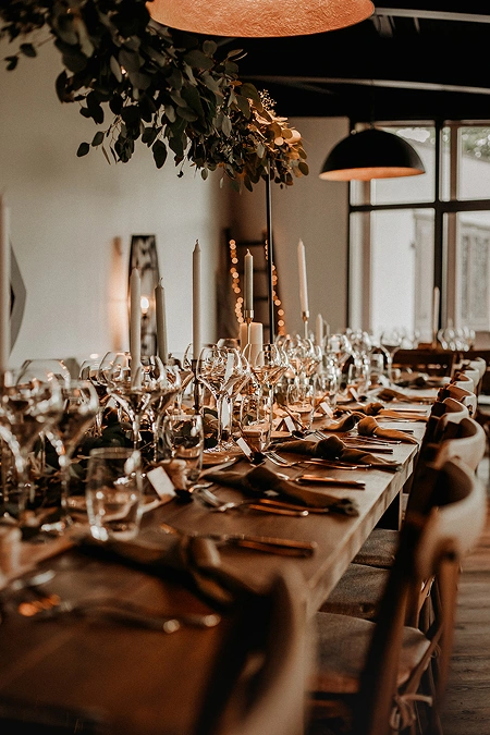 Table de mariage décorée avec des feuillages et des bougies pour une ambiance chaleureuse à La Ferme Marie Hélène.