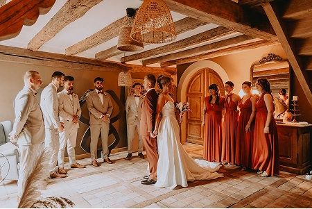 Cérémonie de mariage intime sous une charpente en bois, offrant un cadre rustique et élégant à La Ferme Marie Hélène.