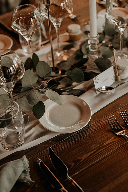 Détail d'une table de réception avec verres et assiettes finement disposés, reflétant l'élégance des événements organisés à La Ferme Marie Hélène
