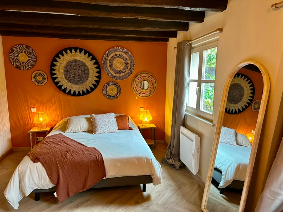 Chambre à la décoration ethnique avec têtes de lit en rotin, créant une atmosphère chaleureuse à La Ferme Marie Hélène.