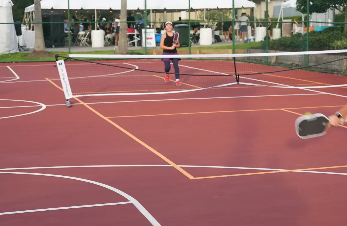Players competing on a red basketball court marked with orange pickleball tape lines, showing how confusing the extra markings were.