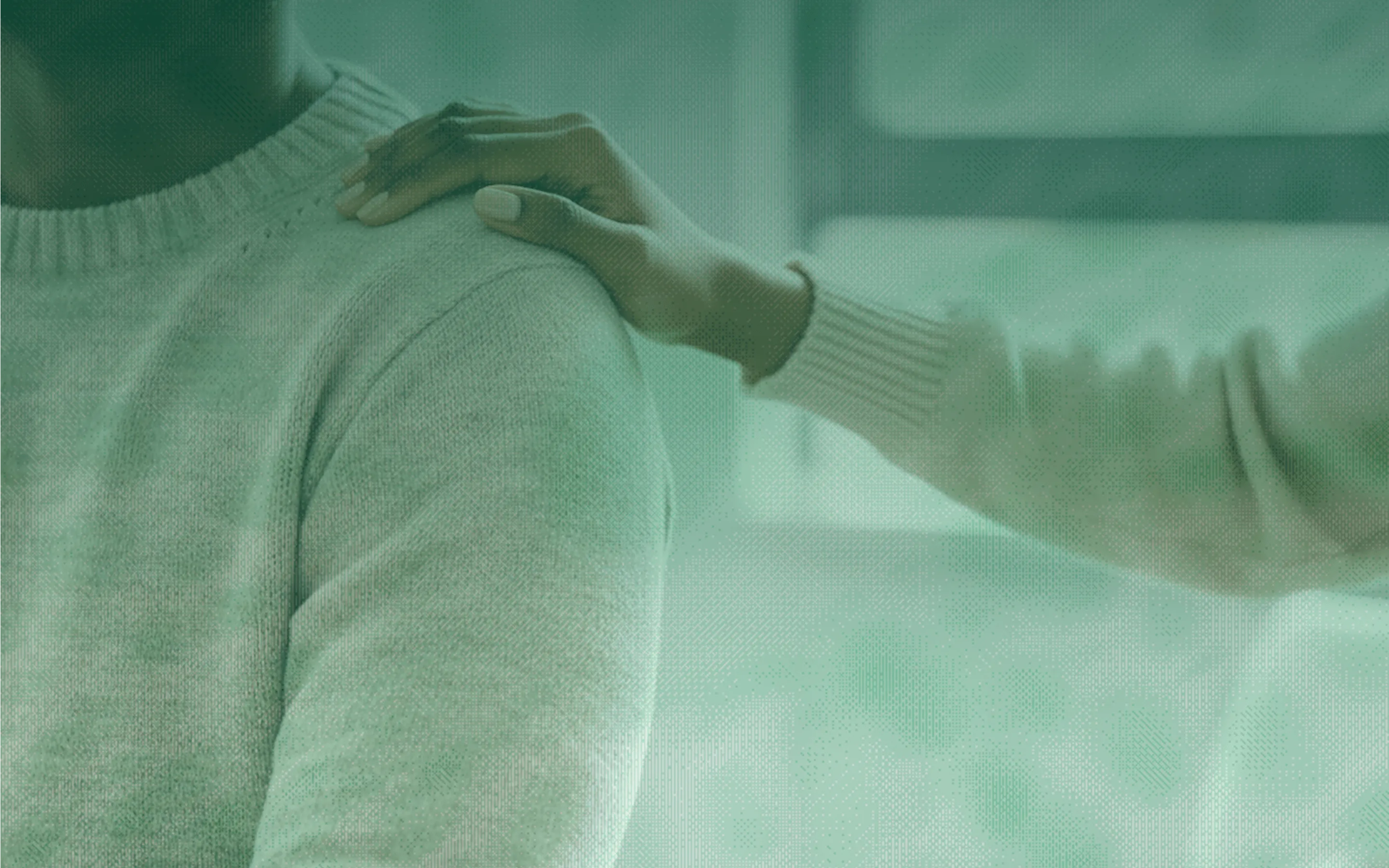 A woman in a white sweater is touching another woman's hand.