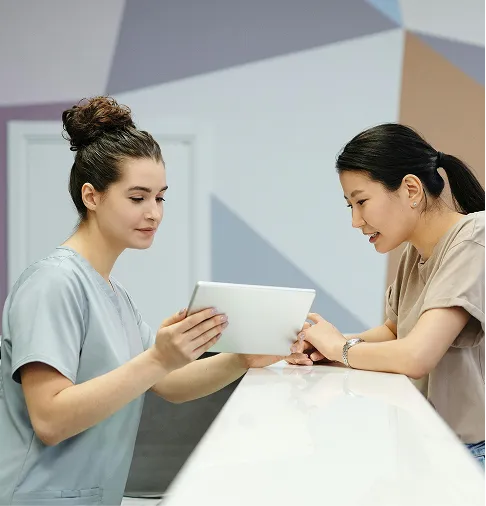 Two young women are looking at a tablet.