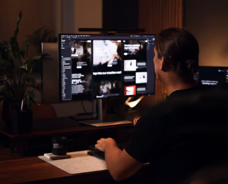 Robin at a dual-monitor desk in the evening