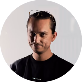 Man with glasses on his head wearing a black shirt against a light background.