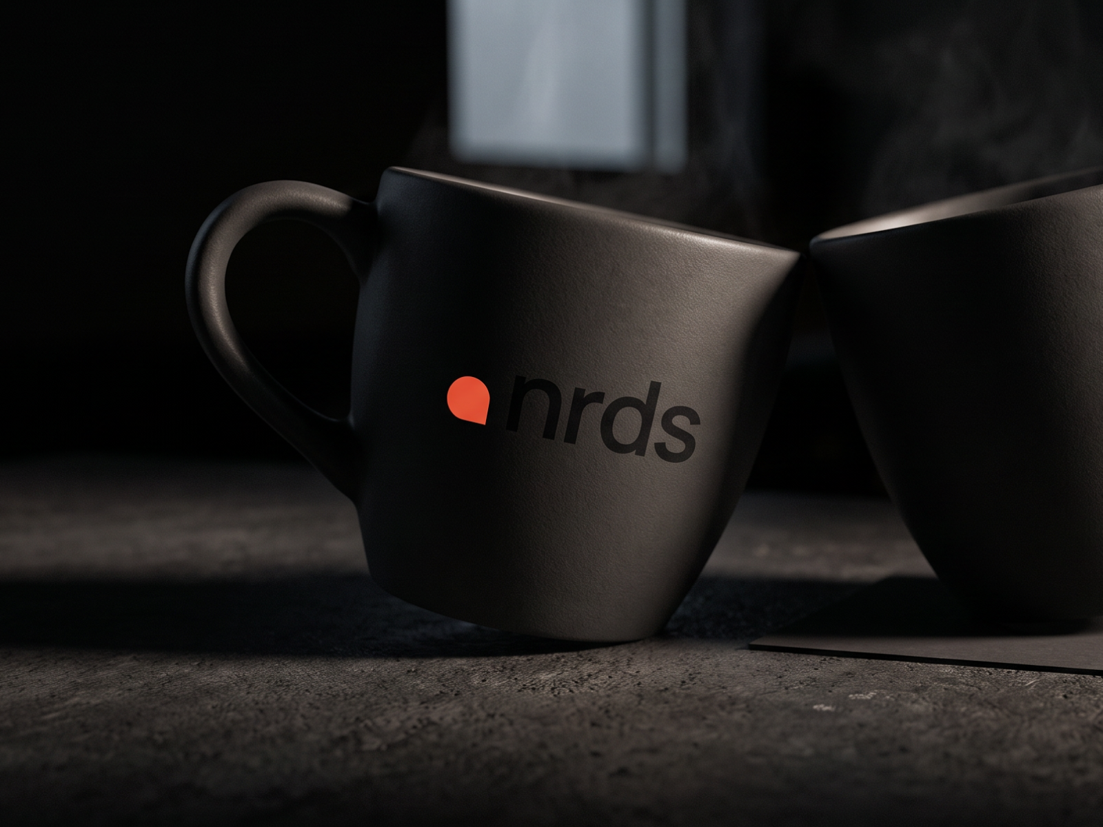 nrds brand identity by Digitalmakers on two dark ceramic mugs