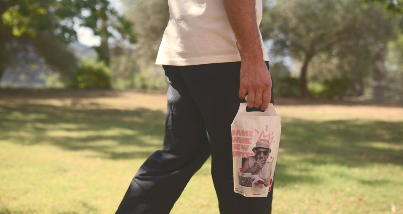 Someone walks across a lawn carrying the Bowi pouch by its handle
