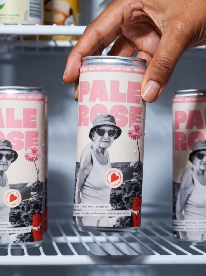 A hand takes a Bowi can from a row of cans in a fridge
