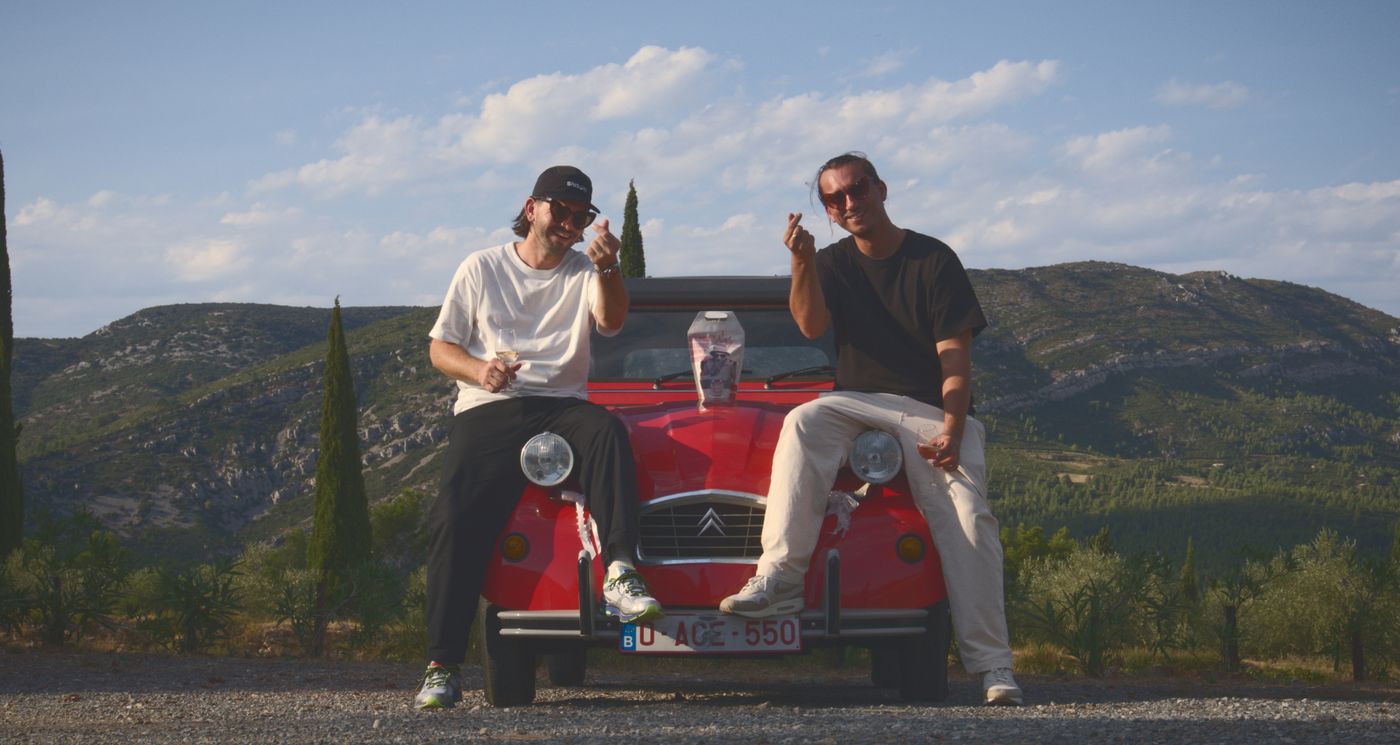 Two of the founders on the bonnet of a red Citroën 2CV