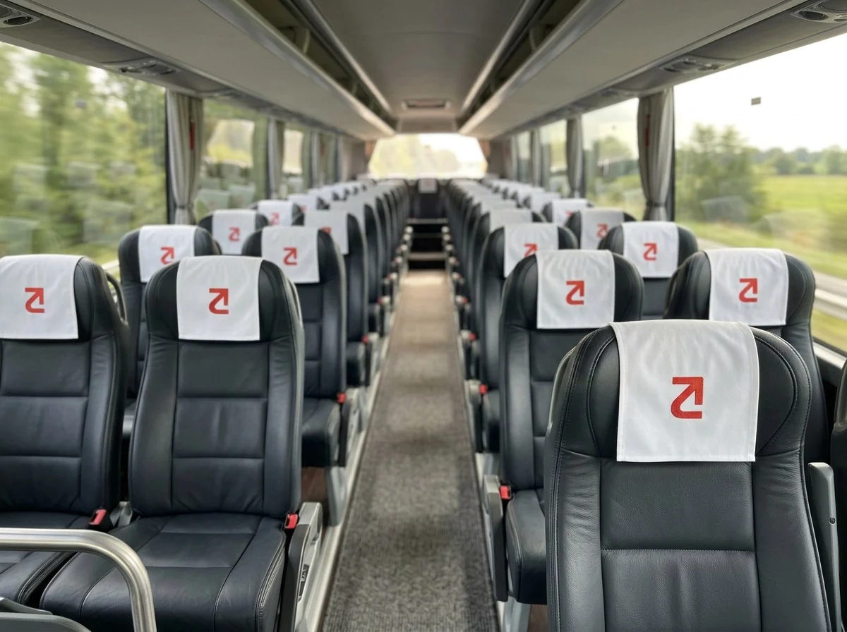 Concept mockup: the inside of a touring coach, every seat with a white headrest cover that carries the red mark