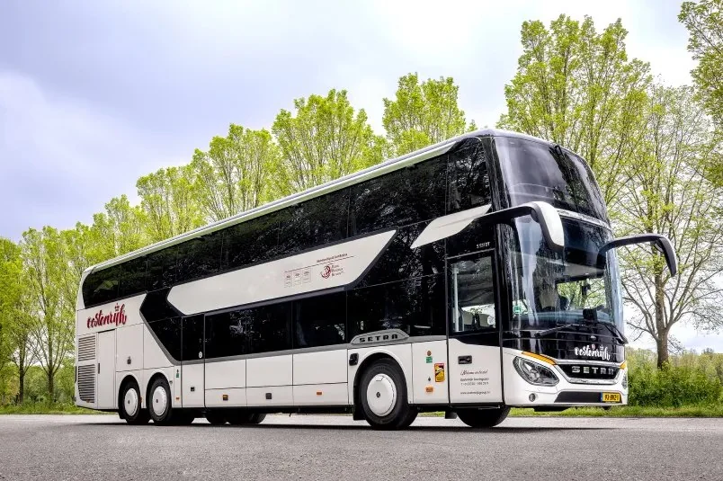 A white double-decker coach of Royal Oostenrijk Group in front of a row of trees