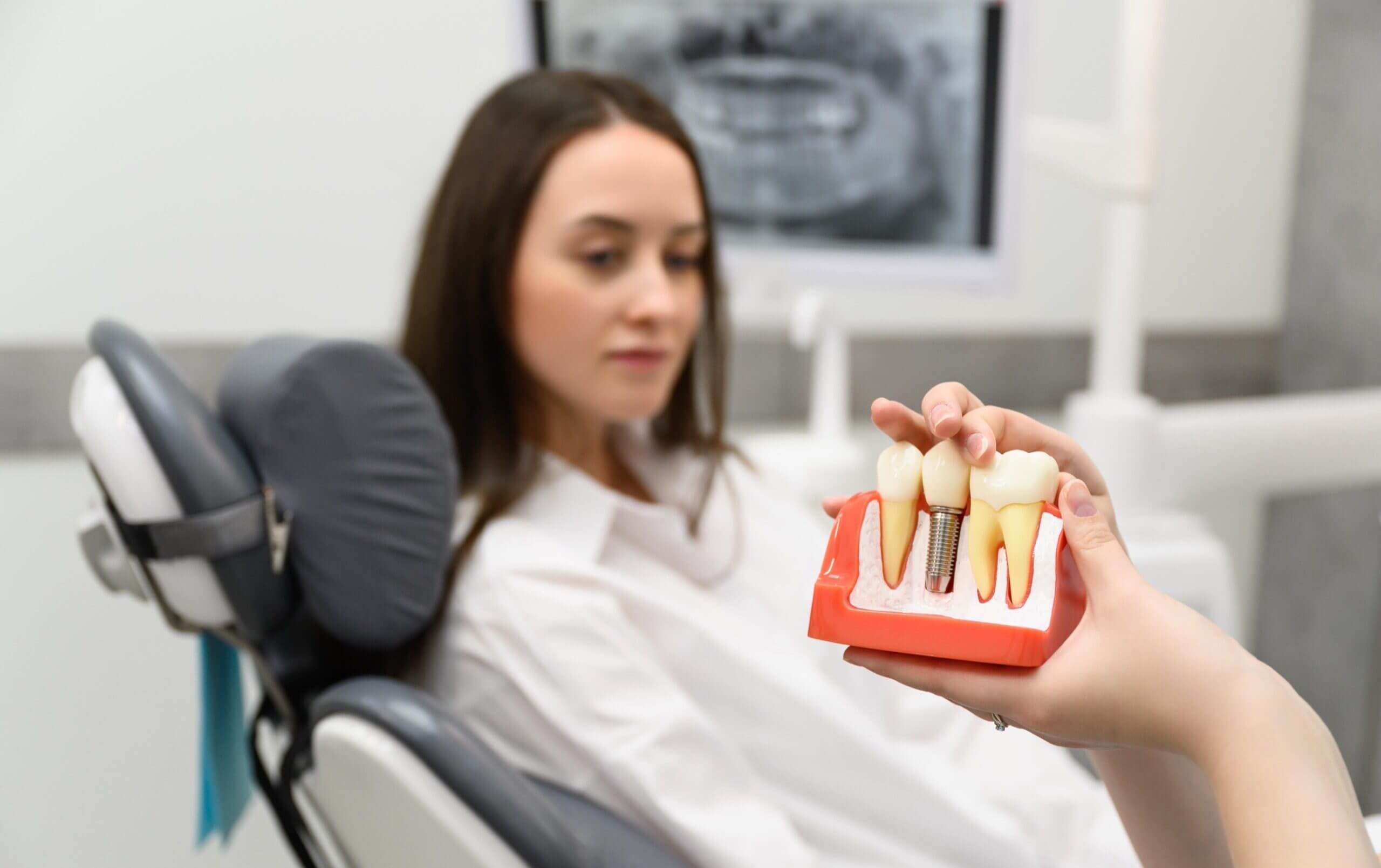 A female patient looking at the implant model while dentist explains.