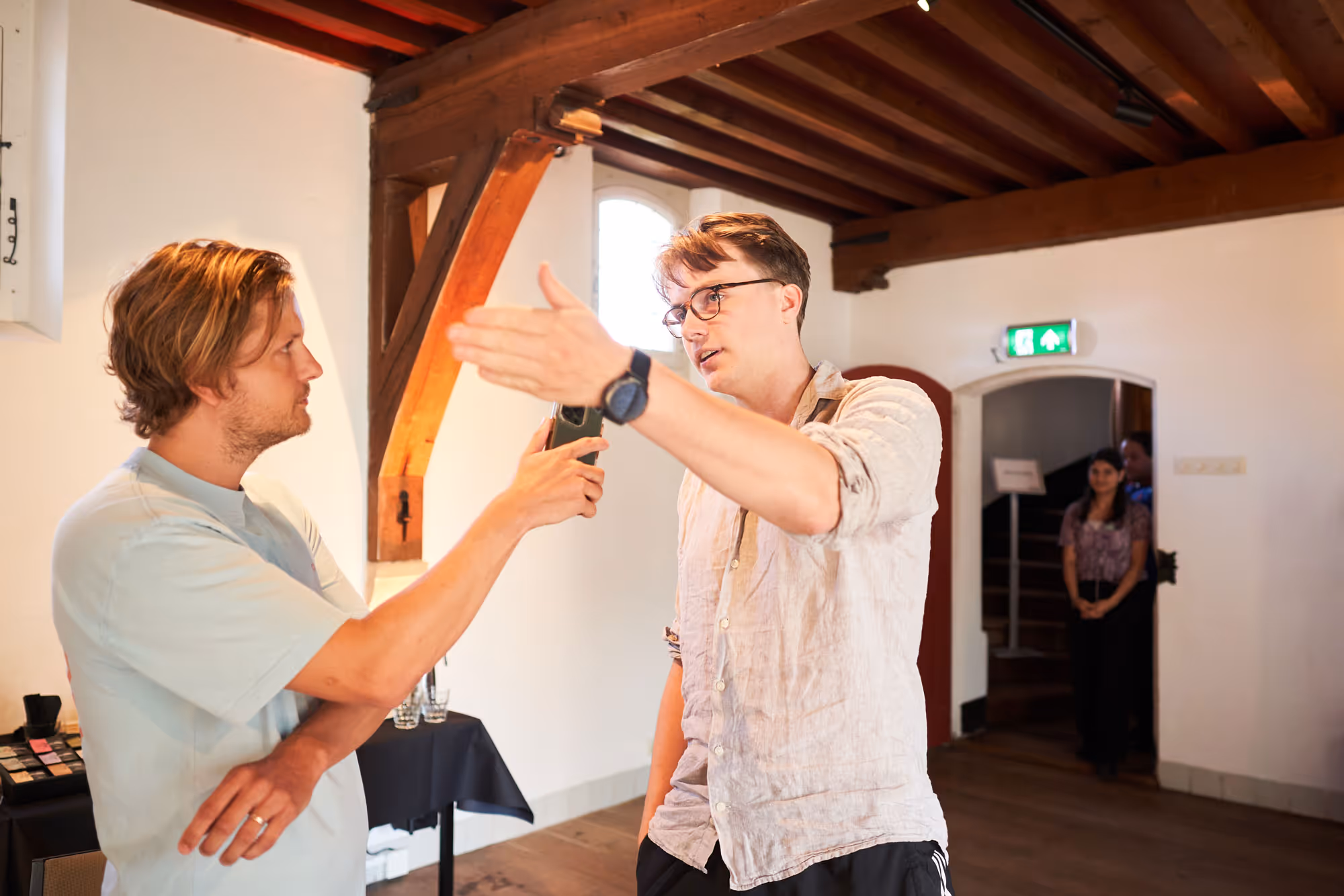 Deelnemer houdt een presentatie terwijl de trainer hem een microfoon voorhoudt