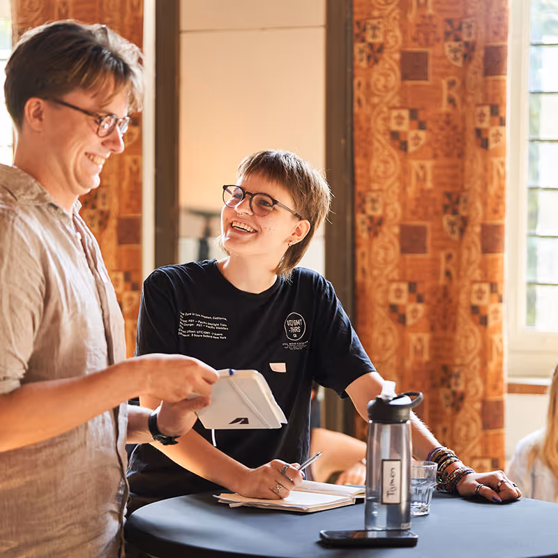Twee deelnemers van Project Apollo samen in gesprek aan een sta-tafel
