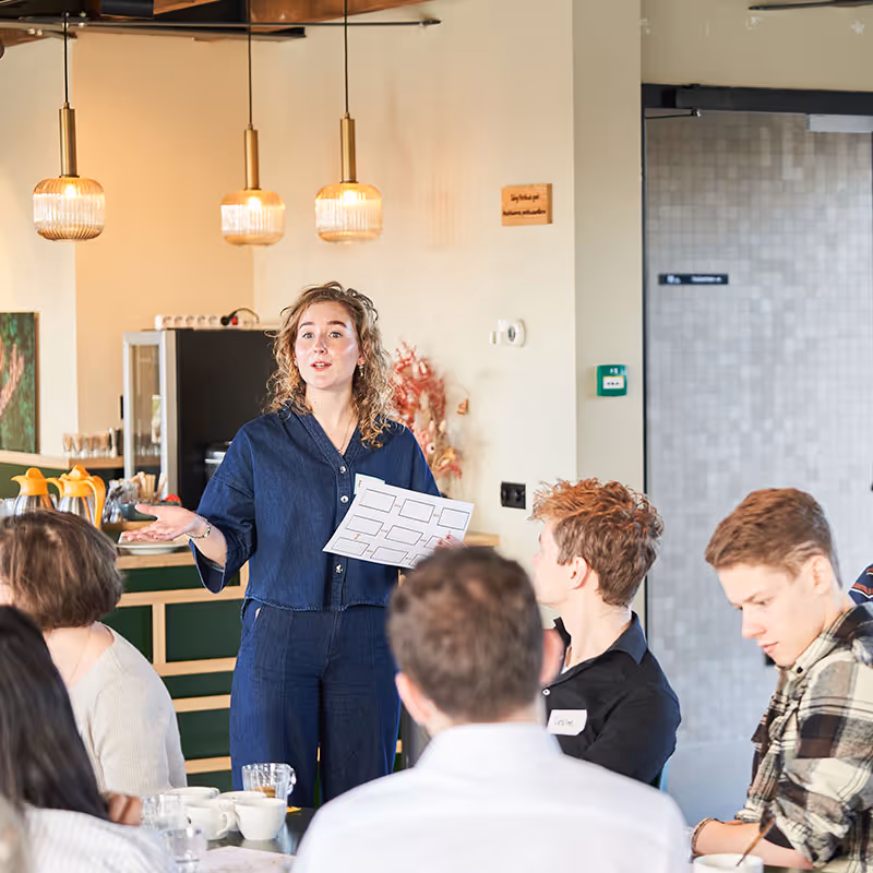 Emma geeft voor een groep deelnemers een presentatie