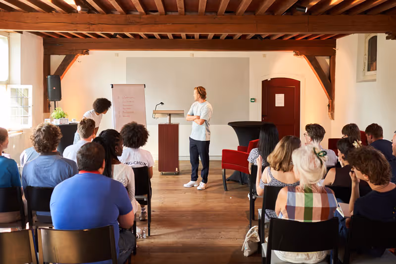 Een foto van alle deelnemers die luisteren naar een presentatie